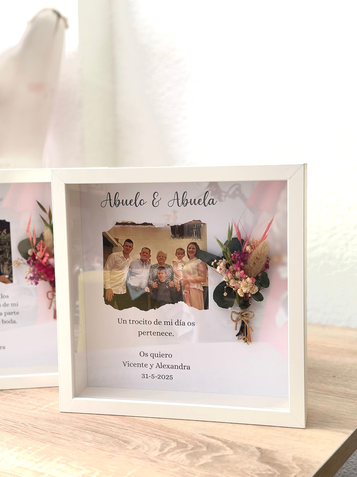 Cuadro con texto, flores preservadas y fotografía.