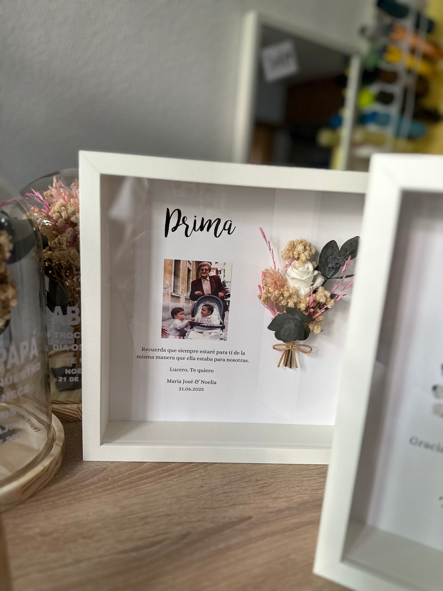 Cuadro con texto, flores preservadas y fotografía.
