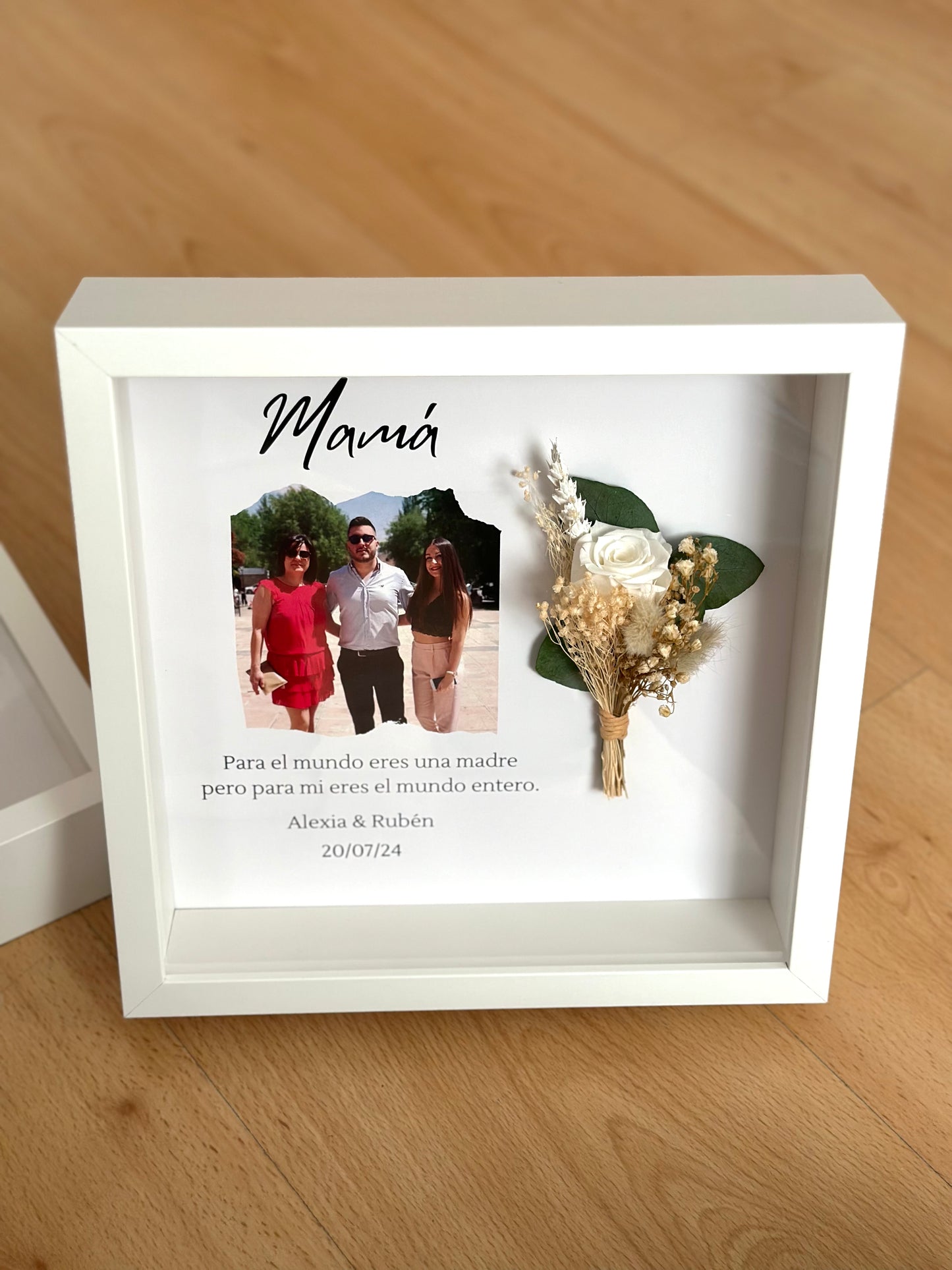 Cuadro con texto, flores preservadas y fotografía.